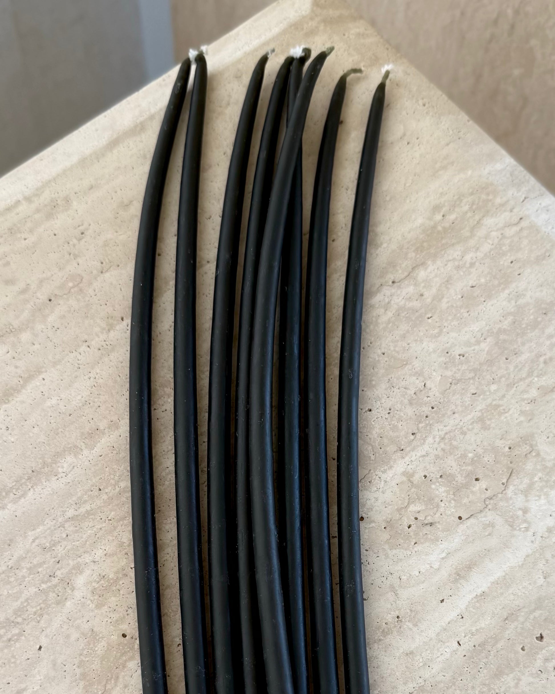 Set of 10 black beeswax taper candles by Belaré Home, elegant and eco-friendly for ambient lighting.