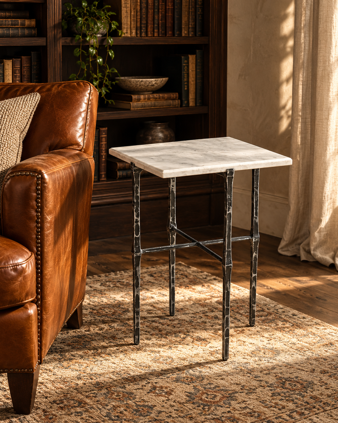 Avelis Marble Accent Table beside a leather armchair in a warm reading room.