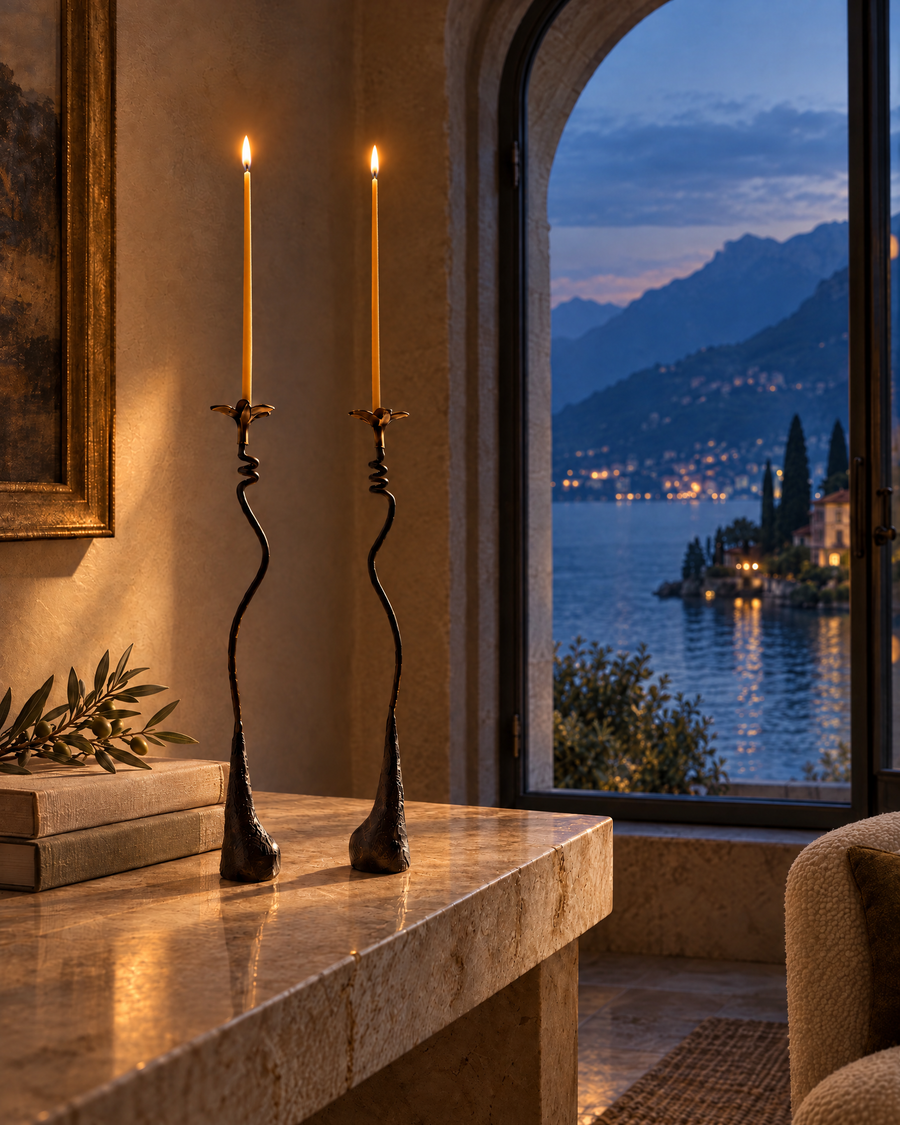 Ferra Lily iron taper holders lit by thin candles on a stone console at dusk